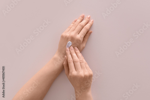 Female hands with cosmetic cream on light background