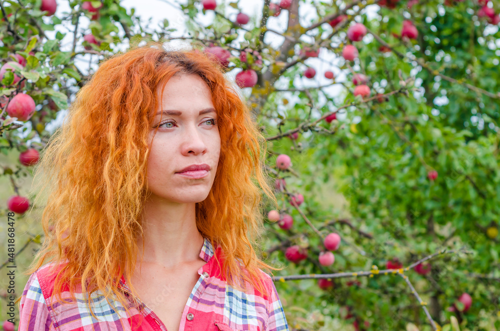 Bright photo of beautiful woman on blurred background of apple orchard. Red hair, blue eyes, pensive look. Bright photo of beautiful woman on blurred background of apple orchard. Red hair, blue eyes, pensive look.