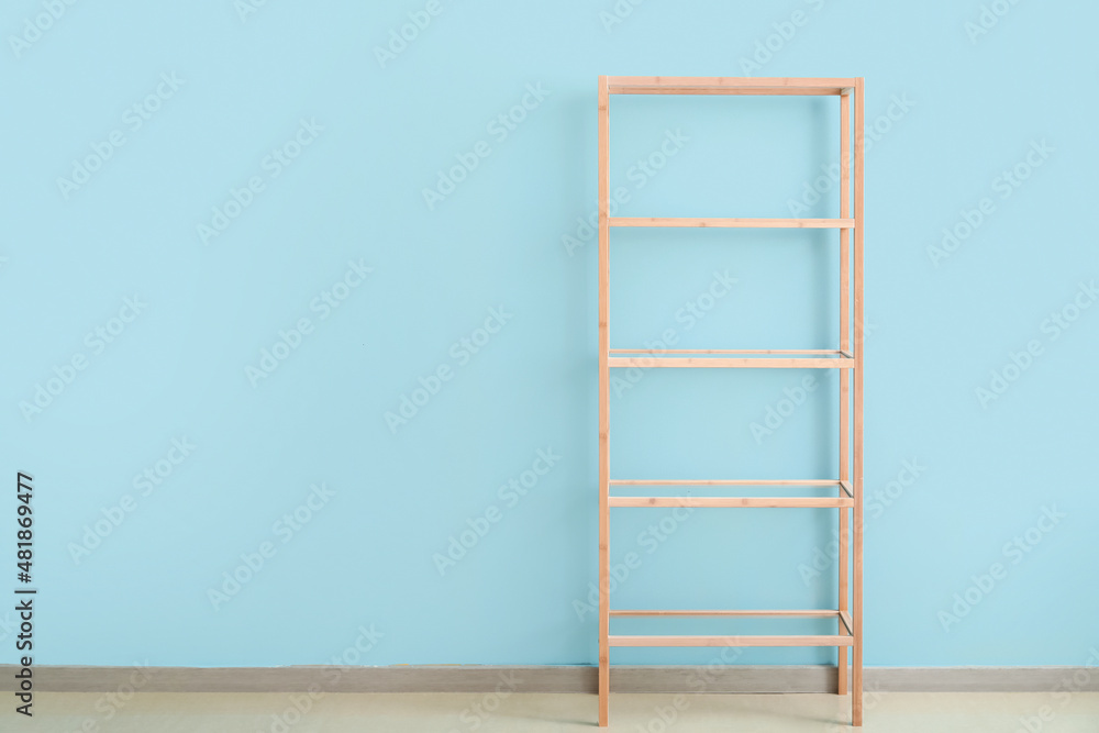 Empty wooden shelving unit near blue wall Empty wooden shelving unit near blue wall