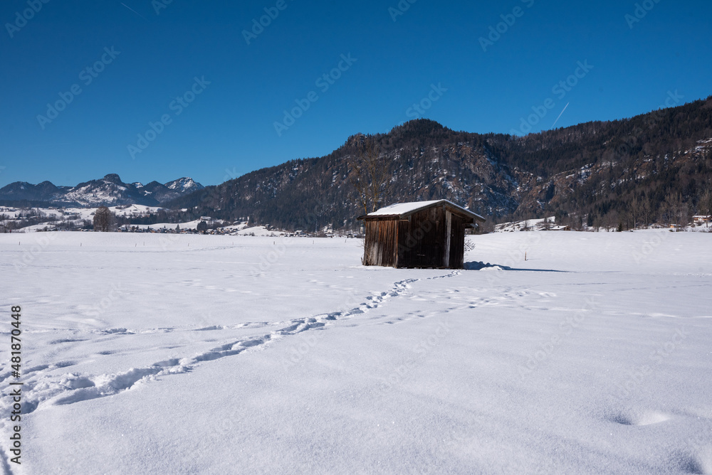 Stadl und Spuren  im Schnee mit bergen im Hintergrund