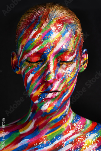Beauty embraces every color. Studio shot of a young woman posing with brightly colored paint on her face against a black background.