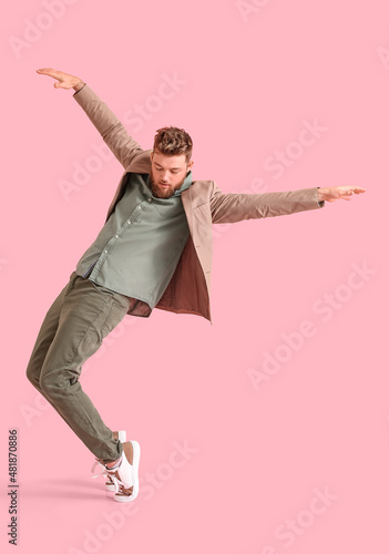 Cool dancing young man on color background photo