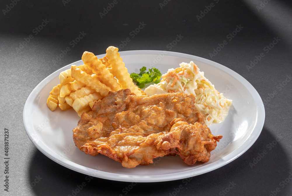 Deep fried breast chicken cutlet with french fries and salad in white dish on dark grey background top view Deep fried breast chicken cutlet with french fries and salad in white dish on dark grey background top view