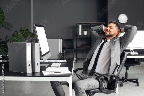 Billede på lærred Smiling young businessman relaxing in office