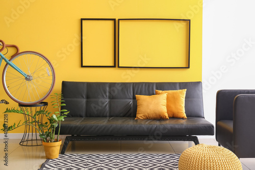 Interior of modern room with bicycle and sofa near yellow wall