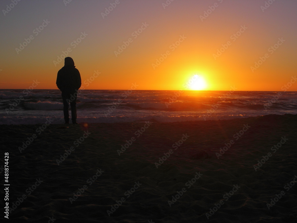 persona mirando la puesta de sol desde la playa