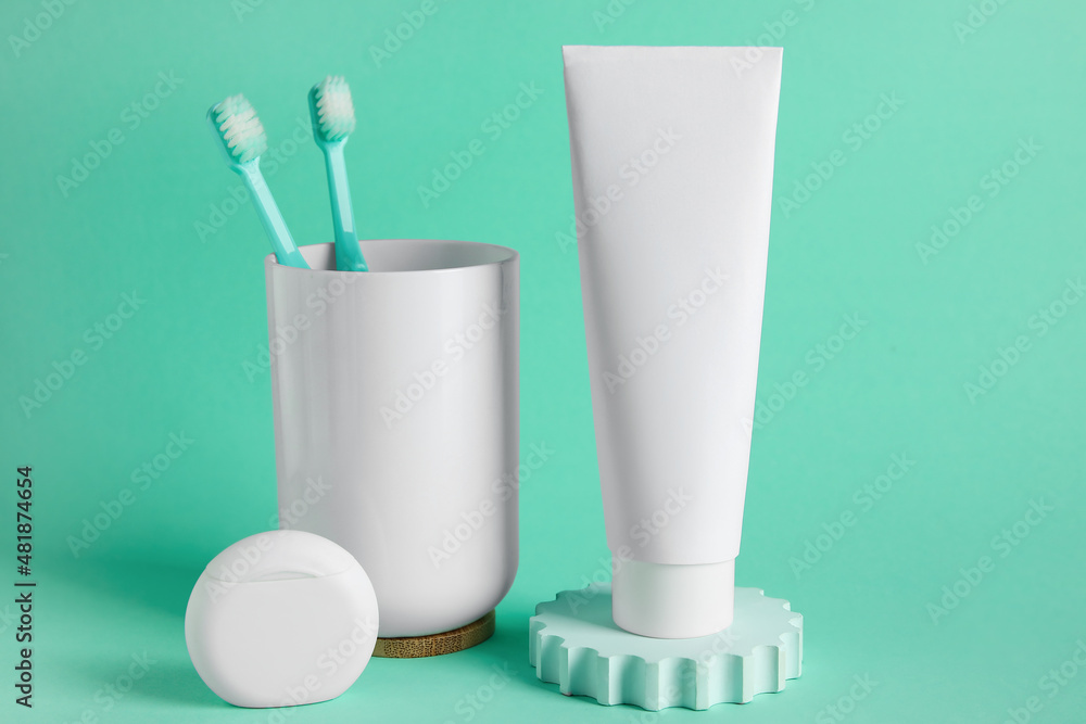 Tube with toothpaste, dental floss and holder with toothbrushes on color background Tube with toothpaste, dental floss and holder with toothbrushes on color background
