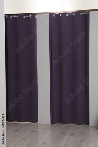 Dressing rooms with stylish purple curtains in fashion store photo