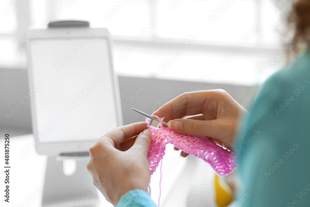 Young African-American woman taking online knitting classes at home, closeup