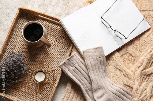 Blank book, cup of coffee, warm socks and eyeglasses on light background