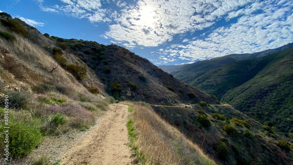 Hiking trail leading down to a winding section through Santa Monica Mountains at Point Mugu State Park, California. Lots of small clouds in sky Hiking trail leading down to a winding section through Santa Monica Mountains at Point Mugu State Park, California. Lots of small clouds in sky
