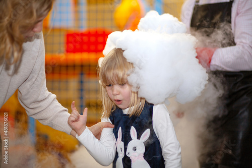 White smoke around the girl's head. Liquid nitrogen at the party. Portrait of a child, laughter and joy, a happy girl.