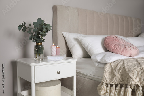 Fotografia Vase with beautiful eucalyptus branches, book and candles on nightstand in bedro