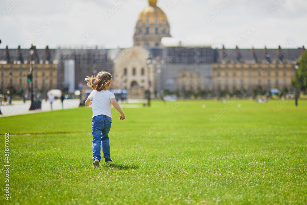 Happy cheerful toddler girl having fun on a street of Paris, near Les Invalides