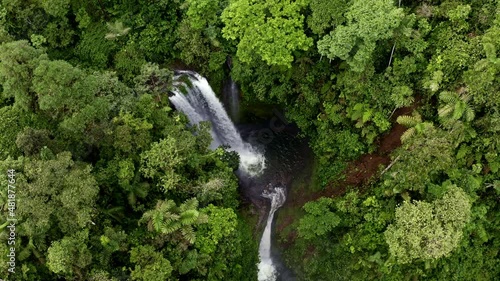 Aerial top view, circling around a beautiful waterfall surrounded by a lush tropical forest: a relaxing nature background