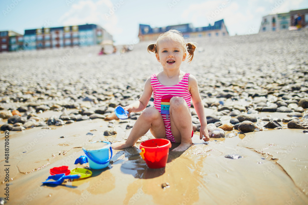 Toddler girl playing on the sand beach at Atlantic coast of Brittany, France Toddler girl playing on the sand beach at Atlantic coast of Brittany, France