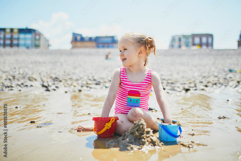 Toddler girl playing on the sand beach at Atlantic coast of Brittany, France