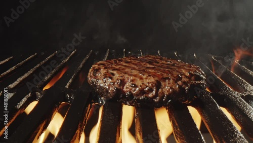 Close up shot of placing burger meat on grill and cooking it on fire