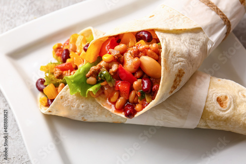 Plate with delicious burritos on table, closeup