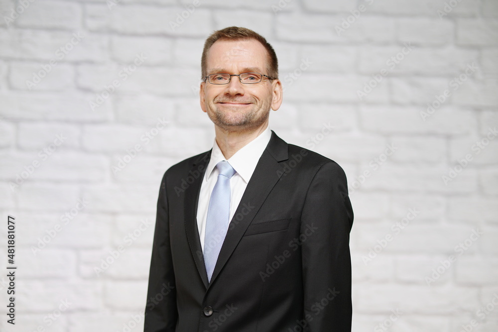 Chef ist stolz und selbstsicher vor Steinwand im Anzug mit Krawatte Chef ist stolz und selbstsicher vor Steinwand im Anzug mit Krawatte