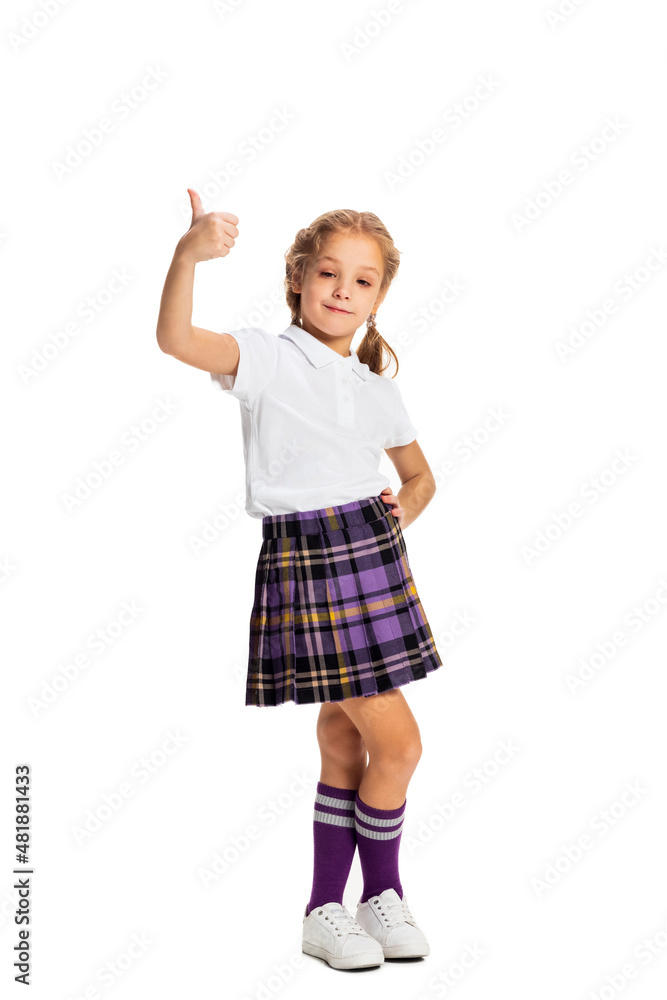 Cheerful child, little girl, pupil in school uniform posing isolated on white background. Concept of childhood, emotions, study Cheerful child, little girl, pupil in school uniform posing isolated on white background. Concept of childhood, emotions, study