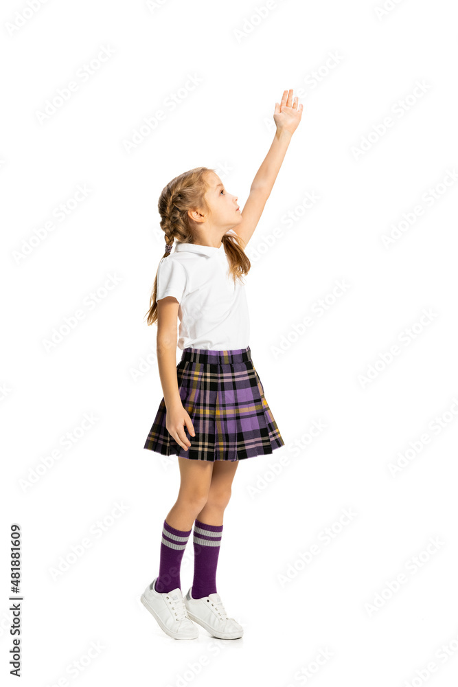 Portrait of cute child, little girl, pupil in school uniform posing isolated on white background. Concept of childhood, emotions, study Portrait of cute child, little girl, pupil in school uniform posing isolated on white background. Concept of childhood, emotions, study