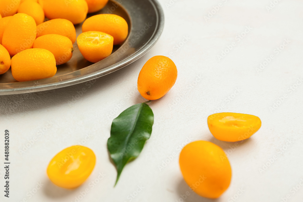 Plate with tasty kumquat fruits on light background Plate with tasty kumquat fruits on light background