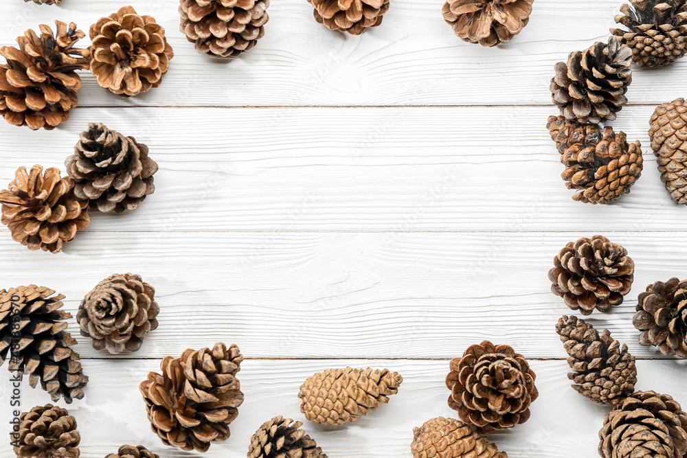 Frame made of pine cones on light wooden background Frame made of pine cones on light wooden background