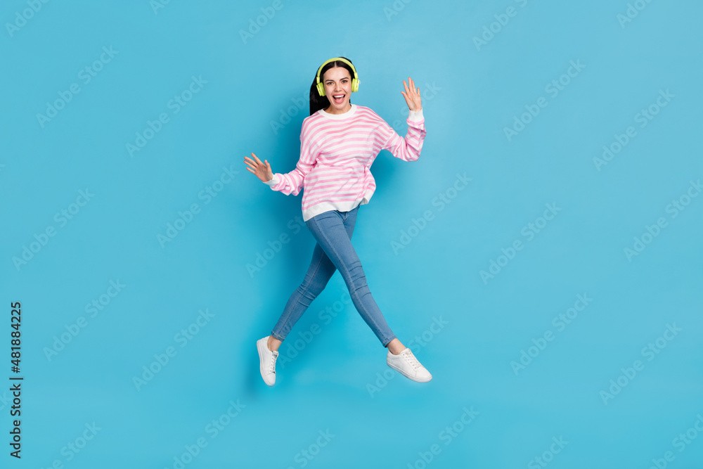 Full length photo of youth girl have fun jumper energetic melody headphones isolated over blue color background