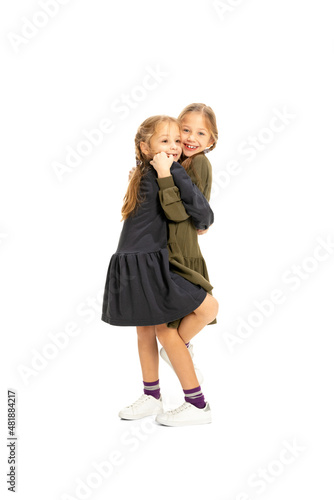 Obraz na płótnie Cheerful little girls, sisters or siblings wearing casual style clothes having fun, playing isolated on white studio background. Concept of childhood, emotions, study w salonie