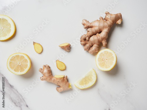a piece of whole and sliced ginger root with lemon slices on the marble countertop. Antioxidant and healing healthy ingredients with vitamins. Top view