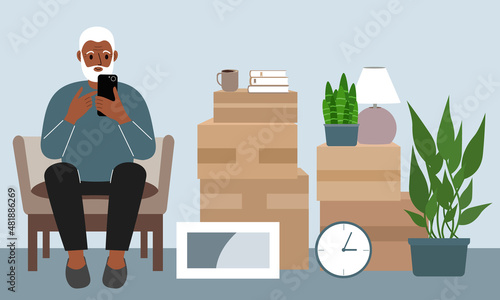 Grandfather at home with a mobile, phone sits in a chair. The concept of online registration of delivery of boxes, goods and assistance in moving.