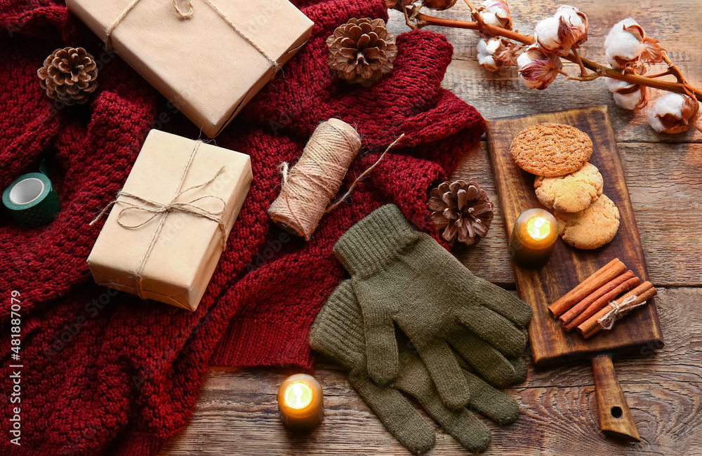 Warm gloves, sweater, gift boxes and cookies on wooden background Stock