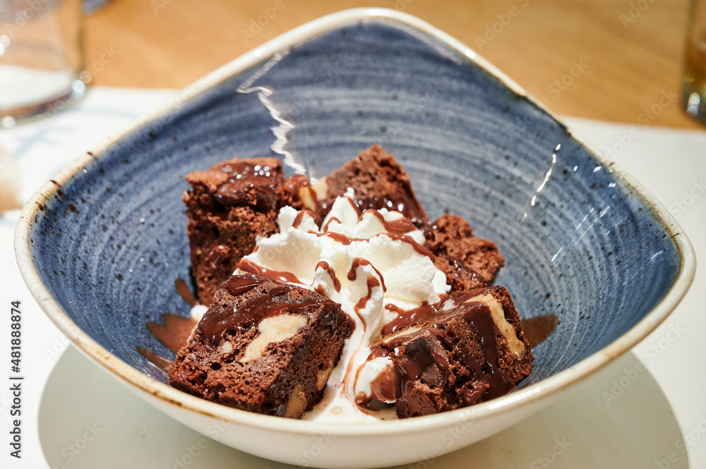Delicious chocolate brownie dessert with cream on modern ceramic plate Delicious chocolate brownie dessert with cream on modern ceramic plate