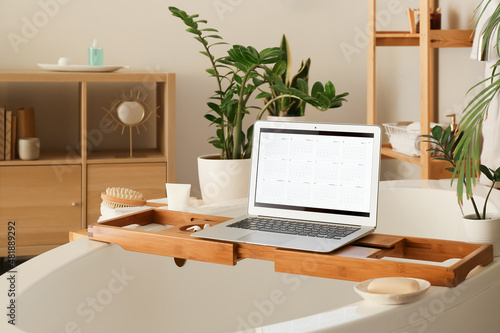 Laptop with digital calendar on tray in bathroom © Pixel-Shot