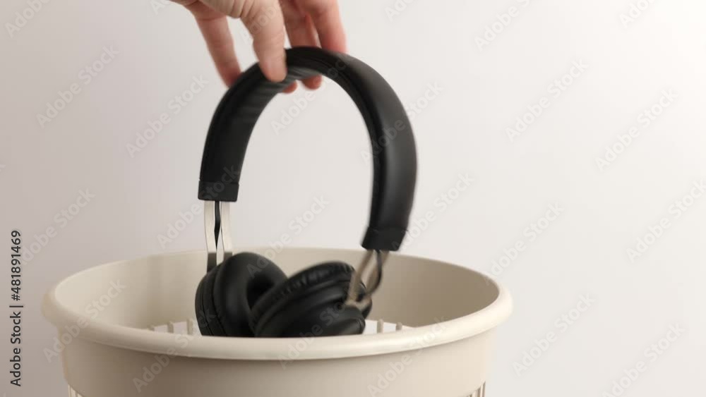 The man throws the headphones in the trash for disposal and recycling The man throws the headphones in the trash for disposal and recycling