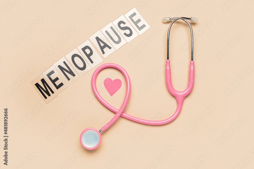 Fototapeta premium Word MENOPAUSE with stethoscope and paper heart on beige background