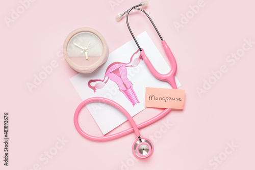 Papers with word MENOPAUSE, uterus, stethoscope and alarm clock on pink background photo