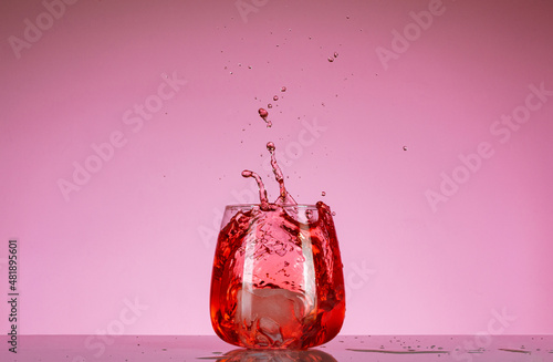 salpicadura de agua con cubitos de hielo en vaso de vidrio
