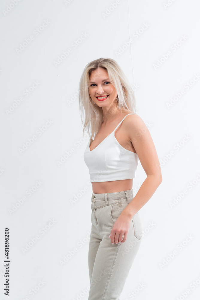 Beautiful blonde in jeans in the studio on a light background. Beautiful blonde in jeans in the studio on a light background.