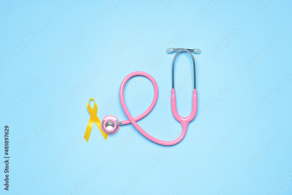 Golden awareness ribbon and stethoscope on blue background. International Childhood Cancer Day Golden awareness ribbon and stethoscope on blue background. International Childhood Cancer Day