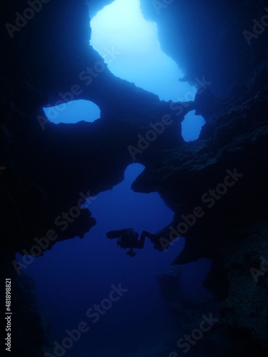 scuba divers exploring the caves and caverns underwater tropical sea fish and corals like skull skeleton cave © underocean