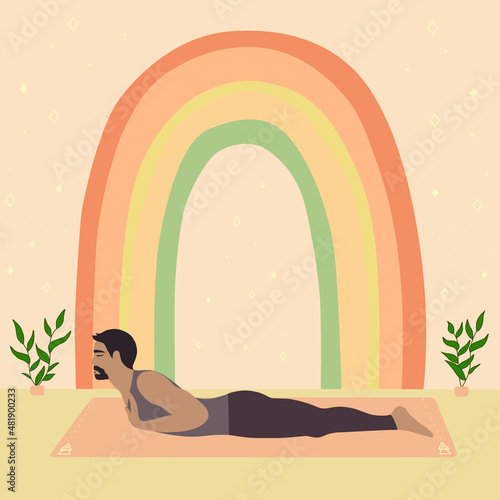 Healthy sporty Asian man doing crocodile or makarasana pose indoors with boho style background 