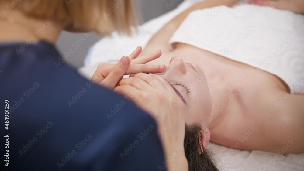Massage session - young woman pushing her fingers on the forehead of her female client Massage session - young woman pushing her fingers on the forehead of her female client