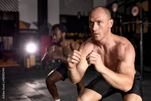 diverse men doing box jump exercise. Cross fit, sport and healthy lifestyle concept. African and caucasian shirtless sportsmen engaged in sport, concentrated and motivated. focus on caucasian male