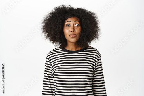 Portrait of cute african american woman looks with desire, yearning, want to try smth, pleading expression, standing over white background © Cookie Studio