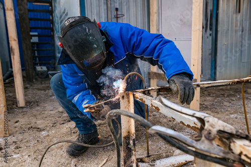 a masked welder does his job, a welder cooks metal © skorikova