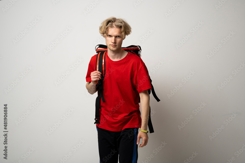 Delivery Service Cocnept. Portrait of male courier wearing red uniform and thermo backpack bag looking at camera isolated on white studio background. Delivery Service Cocnept. Portrait of male courier wearing red uniform and thermo backpack bag looking at camera isolated on white studio background.