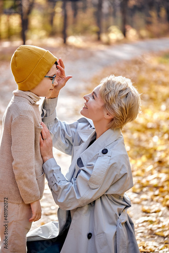 Mother and cute child boy feel love to each other, stand together in park or forest, hugging, talking. sunny day on autumn season. family, lifestyle, people, leisure, love concept © Roman