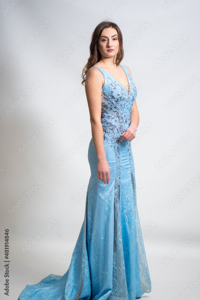 Full body portrait of gorgeous young brunette woman dressed in exquisite nude ball gown with lace top. Attractive female model in elegant strapless dress posing against white background.